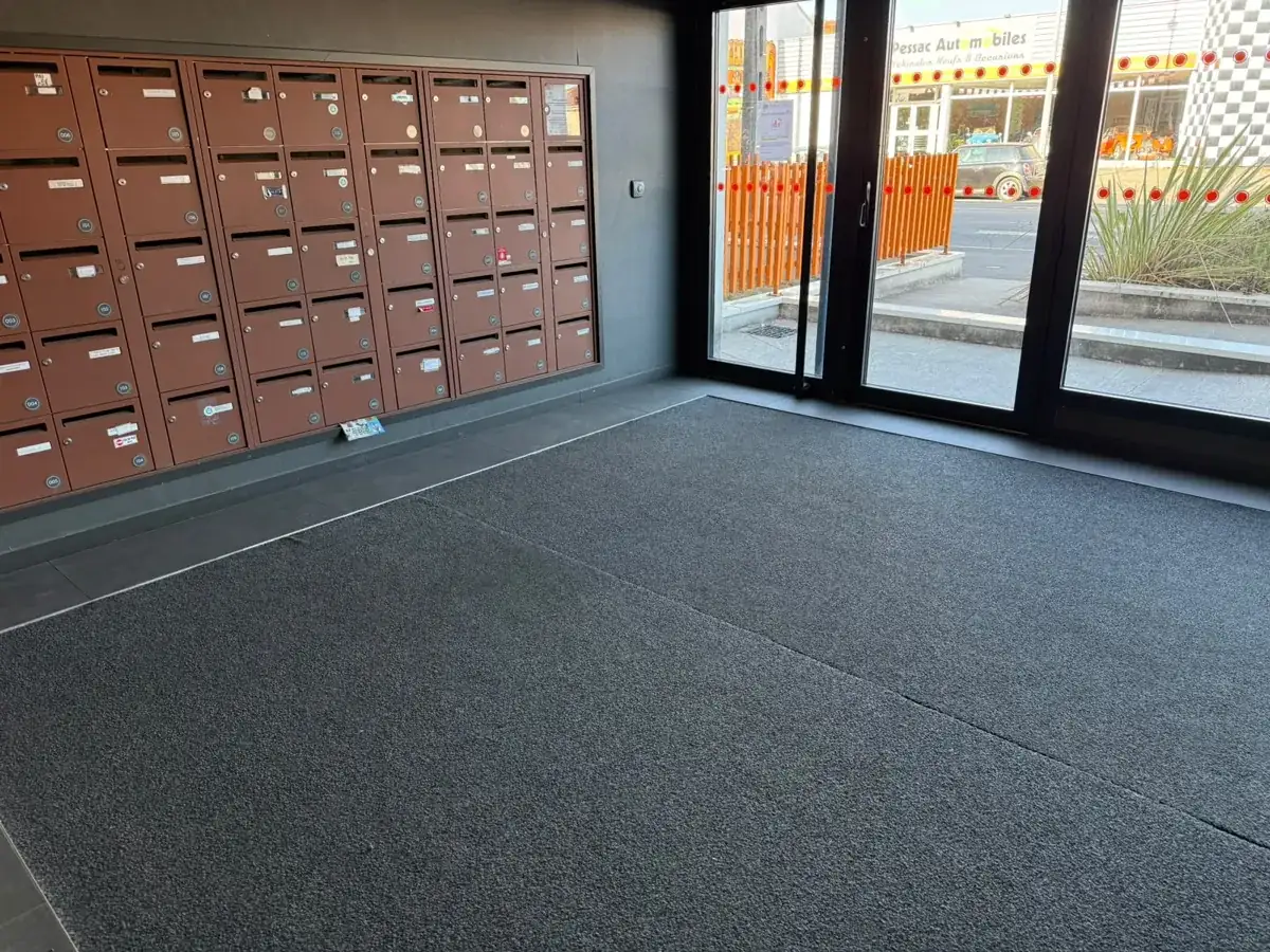 Hall d'entrée d'immeuble avec grand tapis anti-salissures, nettoyé avant l'hiver dans la métropole bordelaise